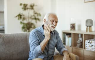 Elderly man with toothache on couch